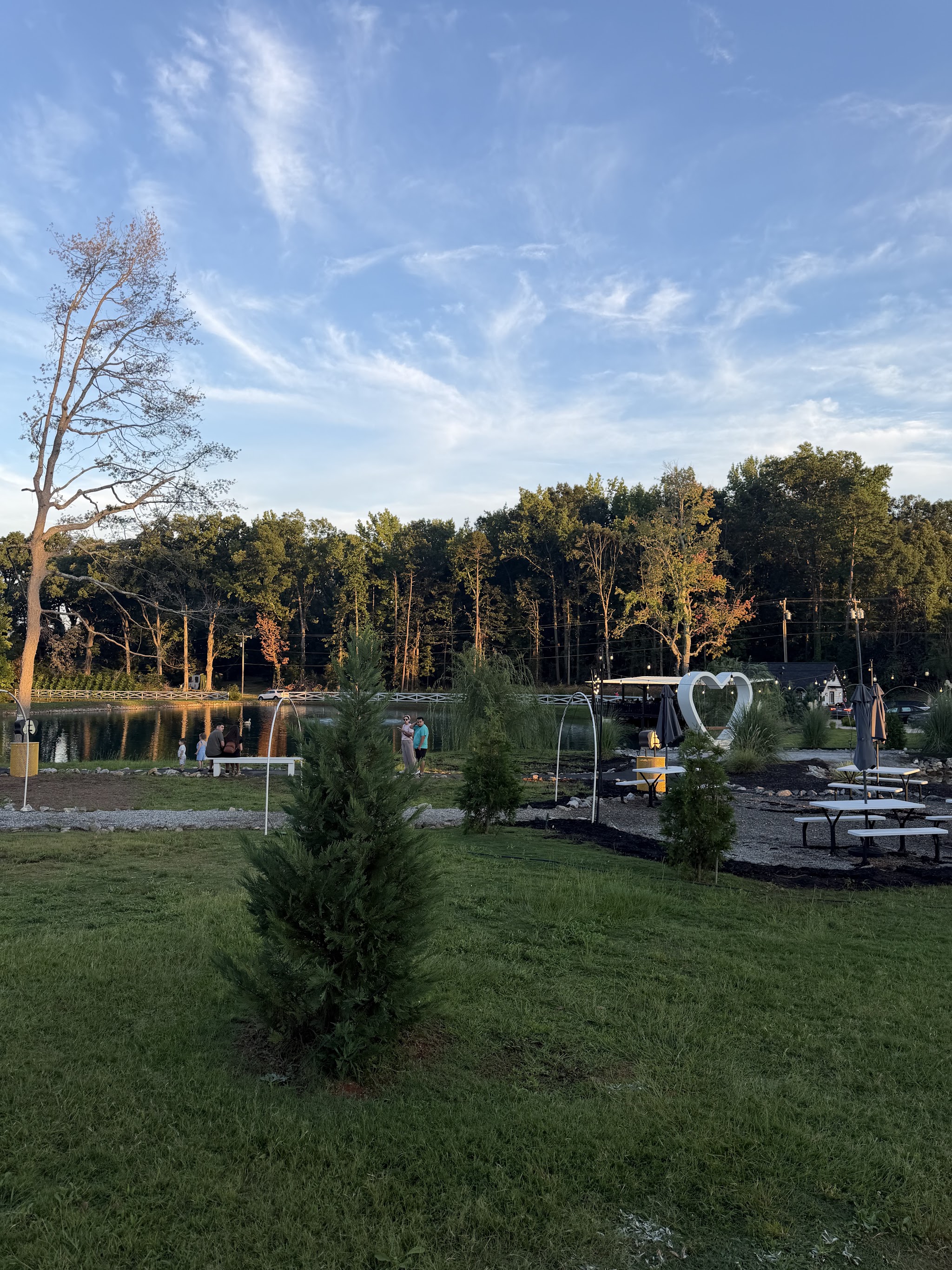 The lakeside seating area with picnic tables and a heart-shaped photo frame at golden hour