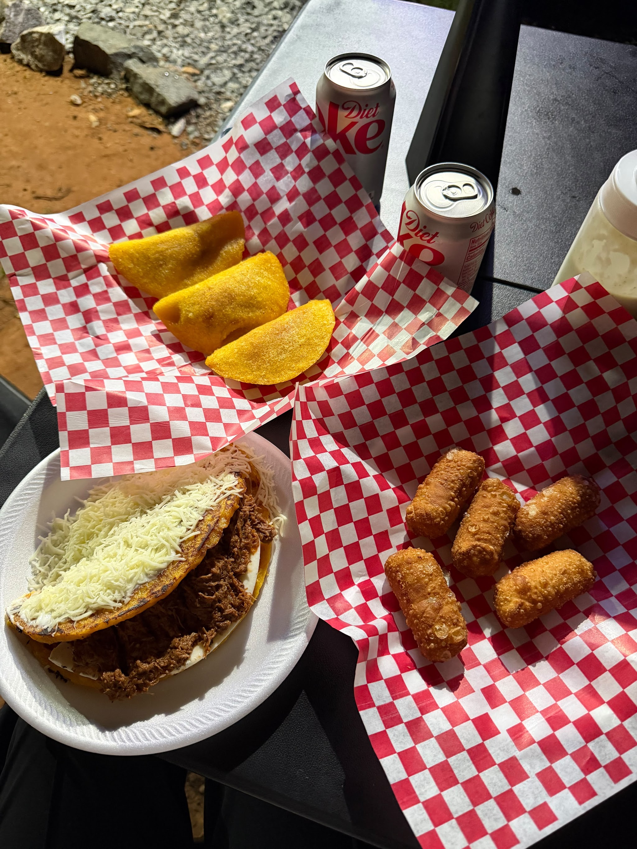 Cachapa with shredded beef and cheese next to empanadas and tequeños